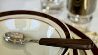 Stack of plates with a spoon on top, placed on a checkered tablecloth.