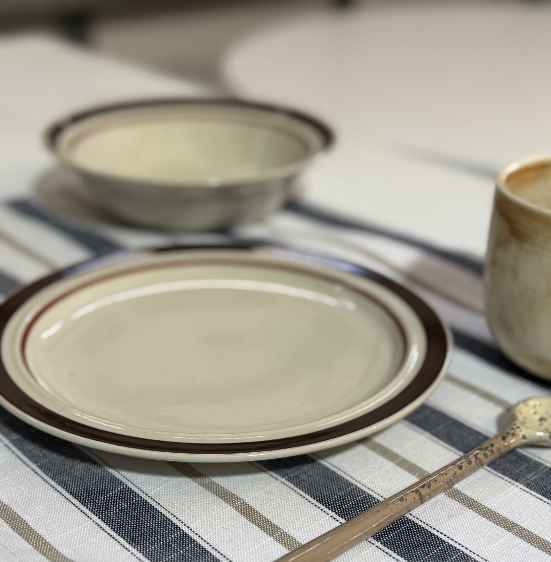 round side plate with brown rim on striped surface
