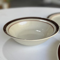 White ceramic bowl with brown rim on a white surface