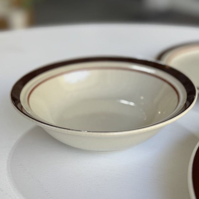 White ceramic bowl with brown rim on a white surface