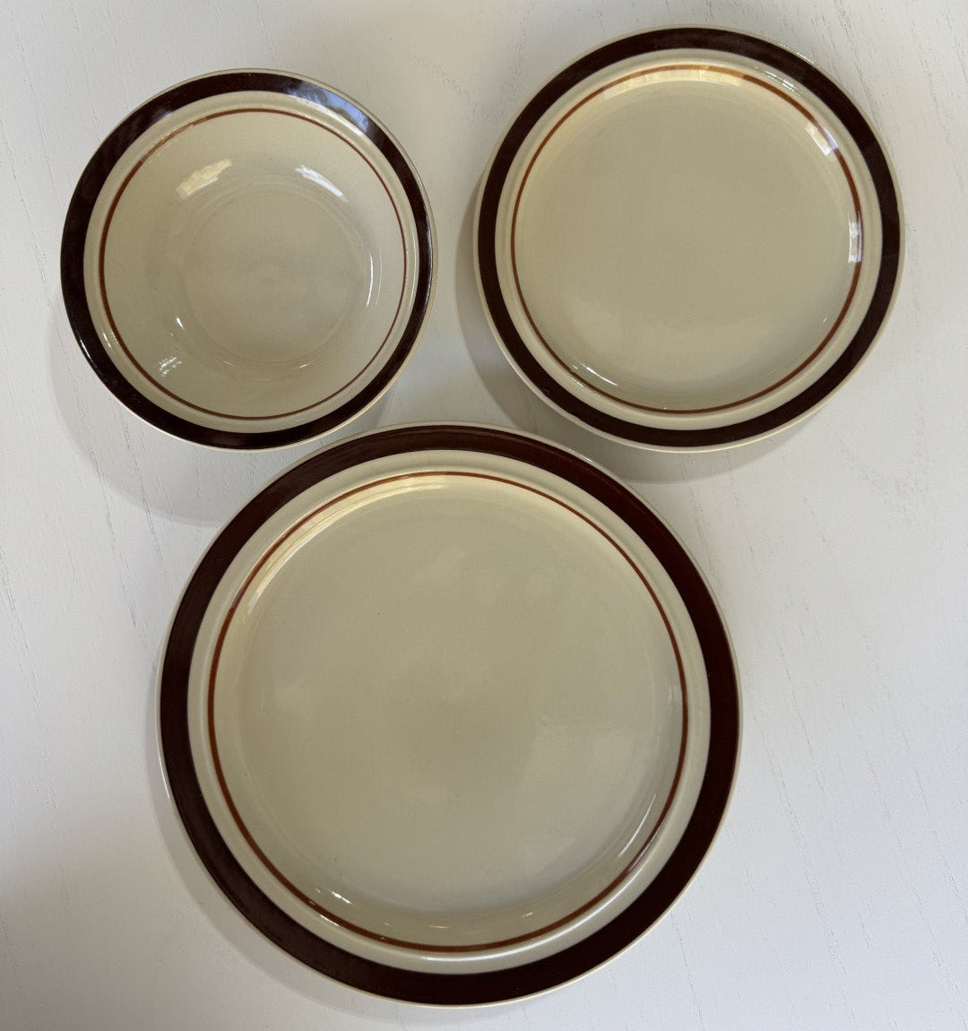 Three ceramic plates with brown rims on a white surface