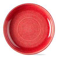 A round ceramic plate with a vibrant red, textured glaze, shown from a top-down perspective on a clean white background.