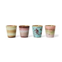 Four ceramic cups with multicolored glaze on a white background