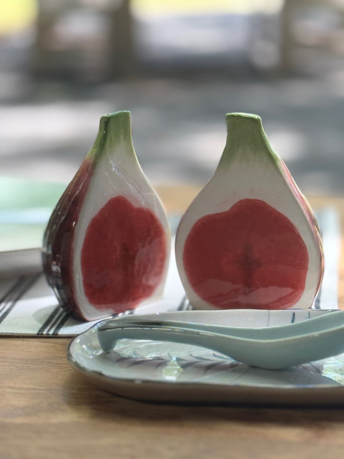 Two ceramic salt and pepper shakers shaped like figs on a wooden table.