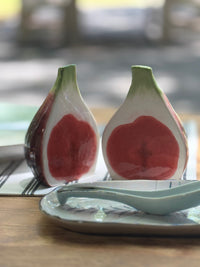 Two ceramic salt and pepper shakers shaped like figs on a wooden table.