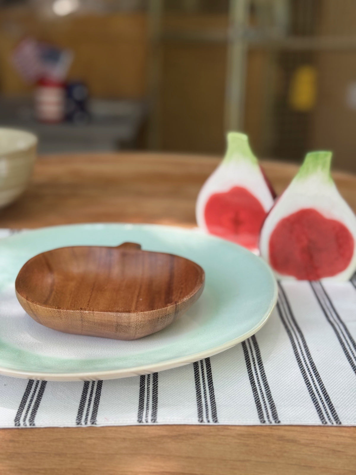 Wooden bowl on a light blue plate with fig -themed salt and pepper shakers in the background.