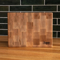 Wooden cutting board with a checkered pattern on a wooden surface with a dark tiled wall background.