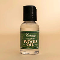 A 29 mL bottle of Scotsman Unscented Wood Oil with a black cap and a green label, set against a solid beige background.