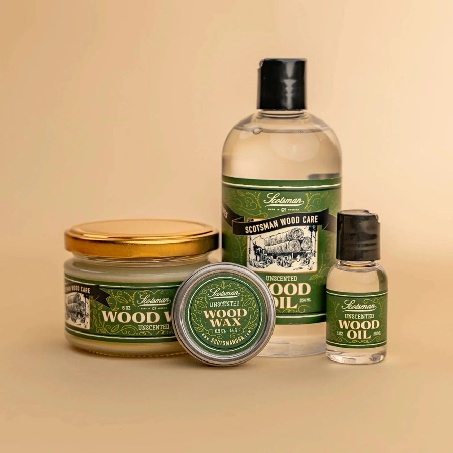 A set of four Lachman Scottish Wood Care products arranged on a warm beige background: a large bottle of wood oil, a small bottle of wood oil, a jar of wood wax with a gold lid, and a tin of wood wax with the lid off.