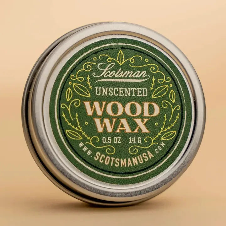 A round metal tin of Scotsman Unscented Wood Wax, featuring a dark green label with gold and white lettering, set against a warm beige background.