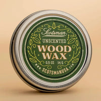 A round metal tin of Scotsman Unscented Wood Wax, featuring a dark green label with gold and white lettering, set against a warm beige background.