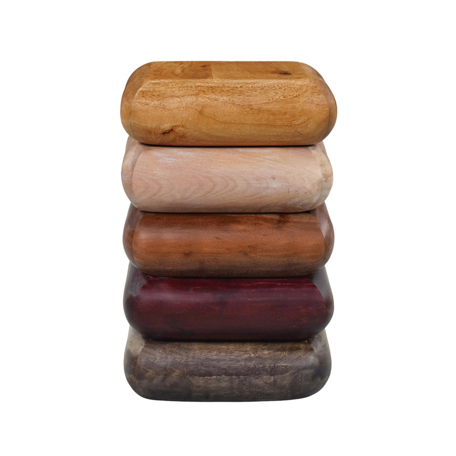 A stack of five handcrafted wooden blocks or coasters in varying wood tones, including light tan, beige, medium brown, dark reddish-brown, and dark gray, set against a plain white background.