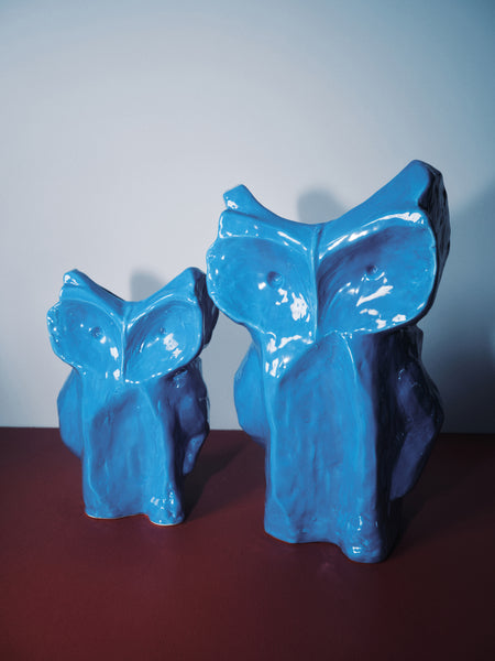 small and large ceramic blue owl vases with maroon and light blue background