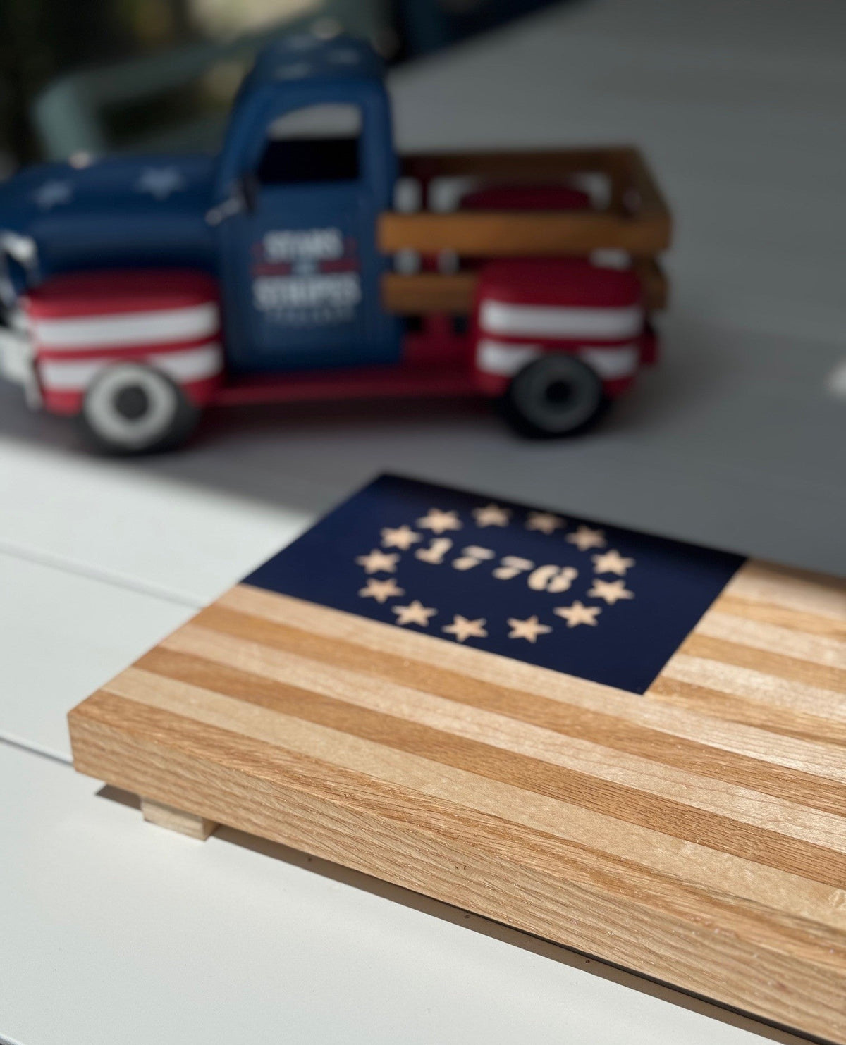 Wooden flag with 1776 design and toy truck in the background