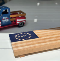 Wooden box with American flag design next to a toy truck on a table.