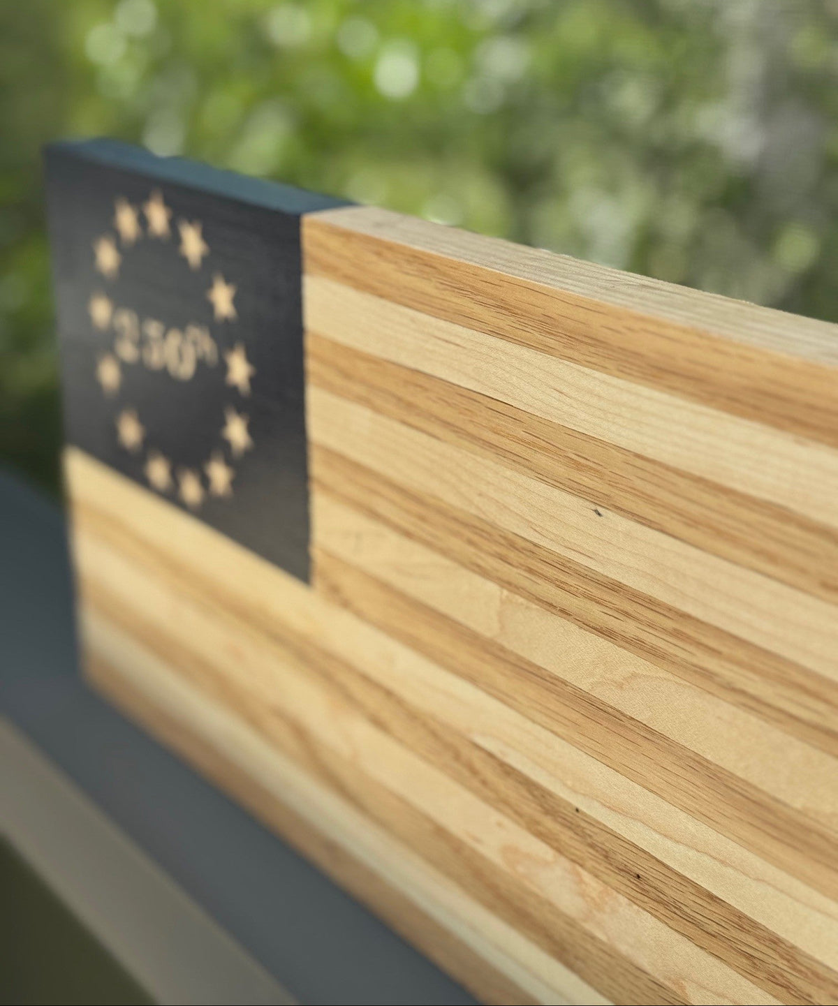 Wooden surface with a black rectangular object featuring star patterns and text, against a blurred green background.