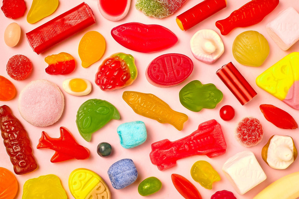 Assorted colorful gummy candies on a pink background
