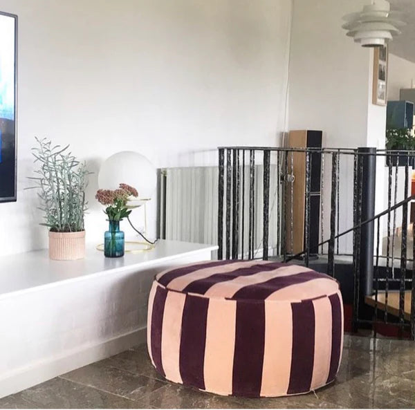 maroon and blush striped ottoman in living room with white walls