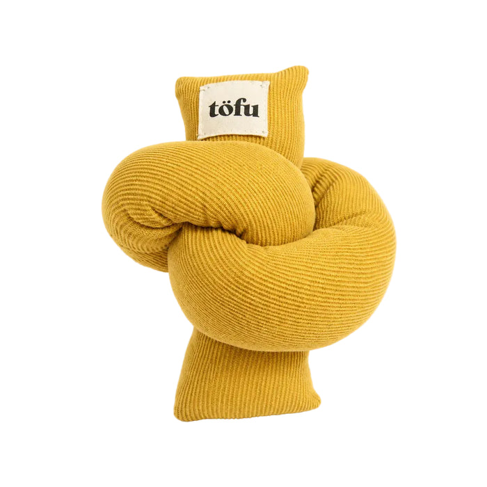 A yellow ribbed fabric dog toy shaped like a twisted knot, featuring a small cream-colored sewn-on label with the brand name 'töfu' printed in black.