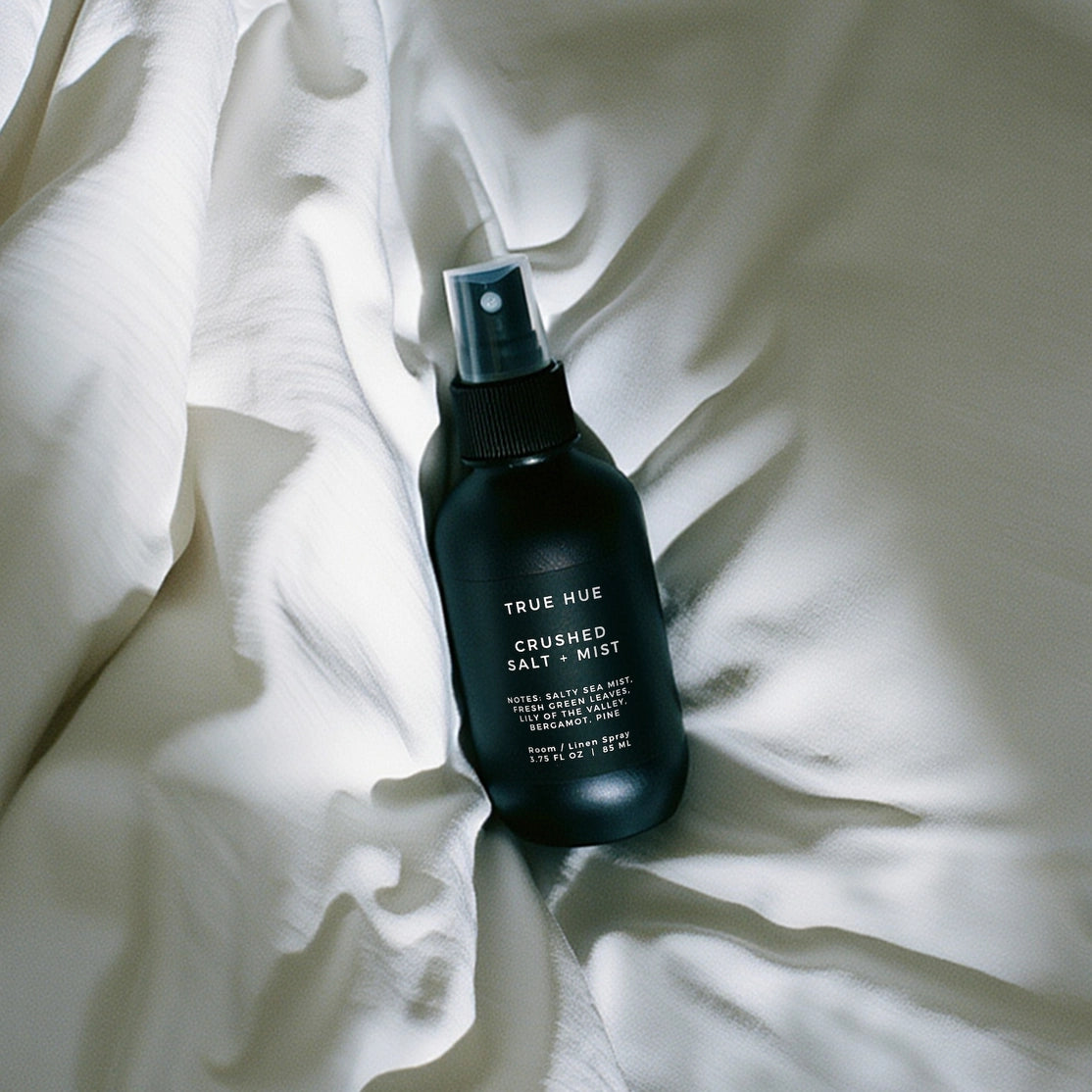 Black spray bottle labeled 'True Hue' on white fabric