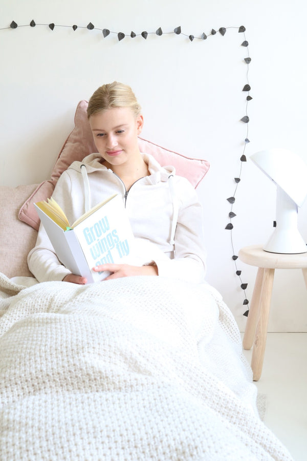 Woman reading a book in bed with a cozy atmosphere