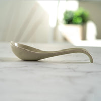 White ceramic spoon on a marble surface with a blurred background