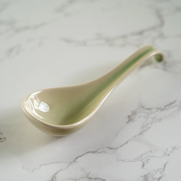Green ceramic spoon rest on a marble surface