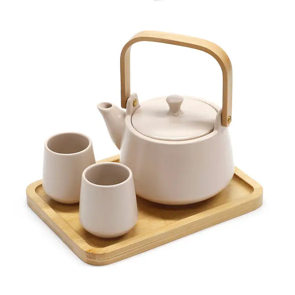 Ceramic teapot with wooden handle and two cups on a wooden tray