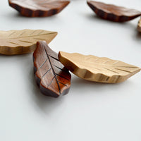 Wooden leaf-shaped coasters on a light surface