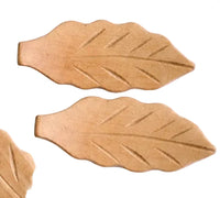 Two leaf-shaped chopstick holders on a white surface