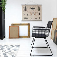 black metal armrest chair with padding in an art studio with paintings 