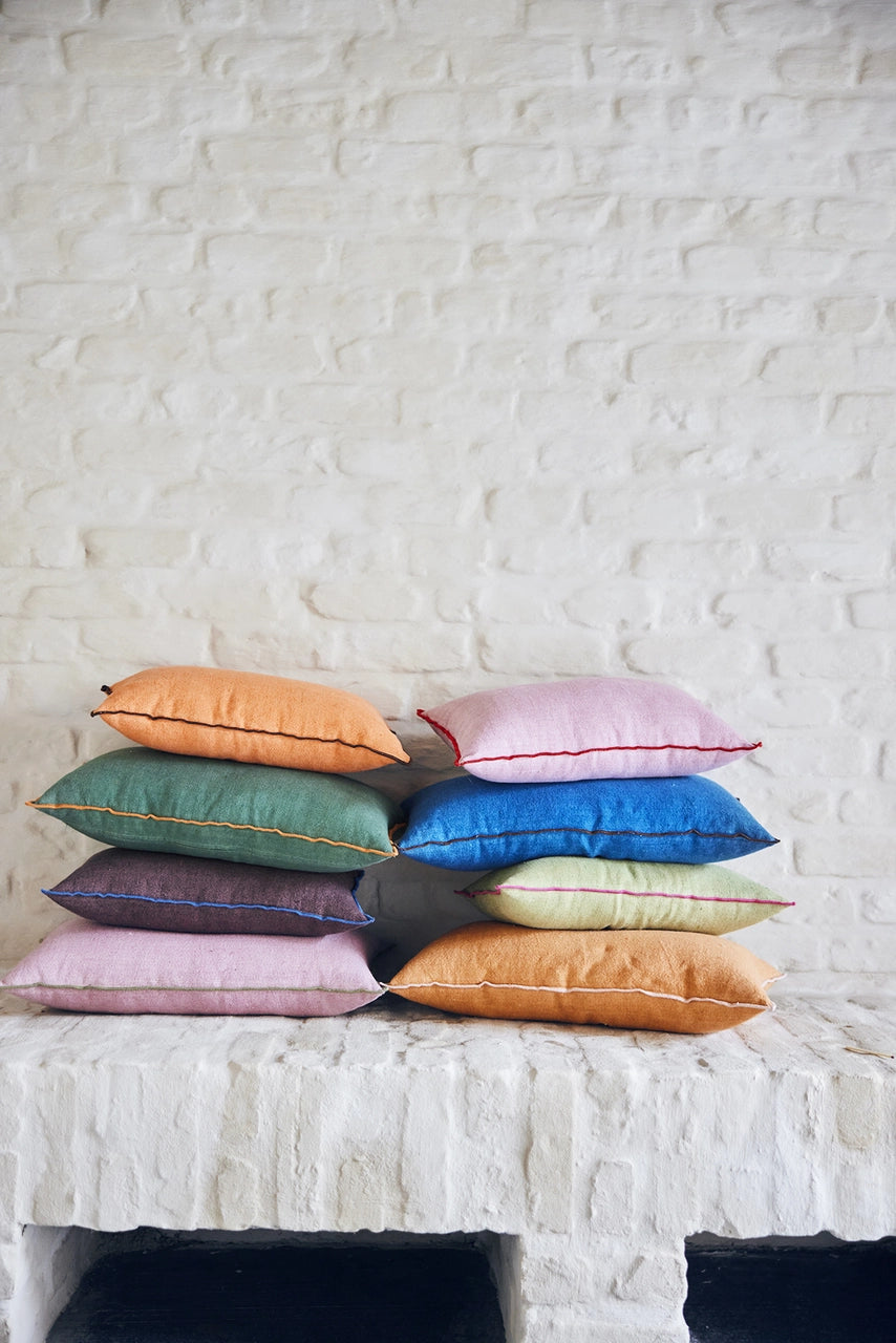 orange, pink, blue, brown and green lumbar shaped pillows in two sizes on two stacks