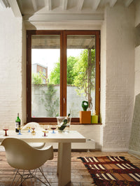 large window with wooden frame and an orage metal box with a green sculpture on top of it