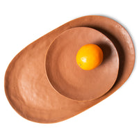 porcelain side plate on top of an oval shaped serving plate and an orange