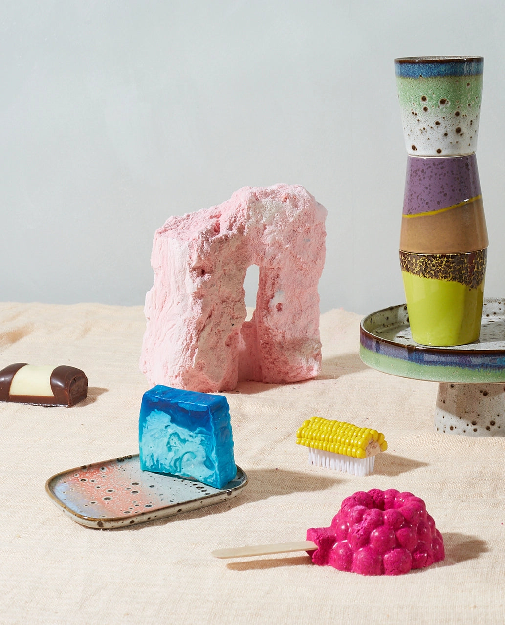 yellow and brown stoneware coffee cup on a table with other cups and a small tray with blue soap