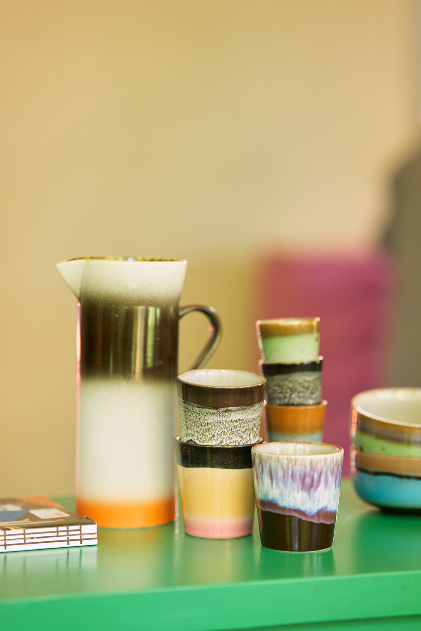stoneware pitcher and tumbler mugs on a green countertop 