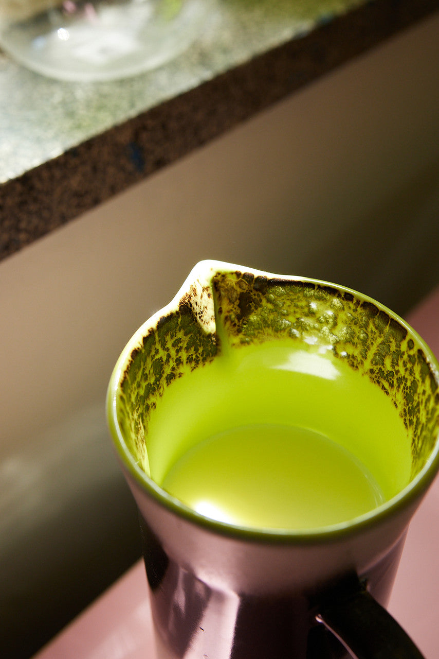 tall stoneware pitcher with orange, white and brown finish with bright yellow inside