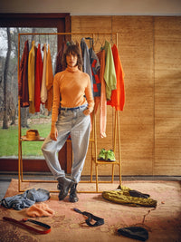 ginger orange metal open wardrobe rack in a room with clothes hanging and a woman standing in front of it