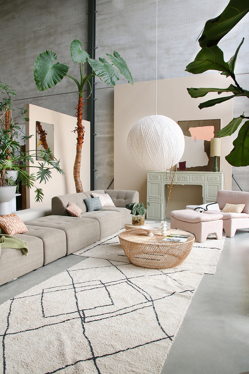 living room with large white bamboo and rice paper pendant light, taupe colored sectional and blush colored fabric lounge chair with ottoman in same color