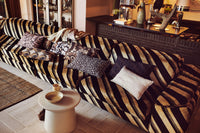 brown vintage style lumbar pillow with white flowers on sofa with other pillows in similar colors