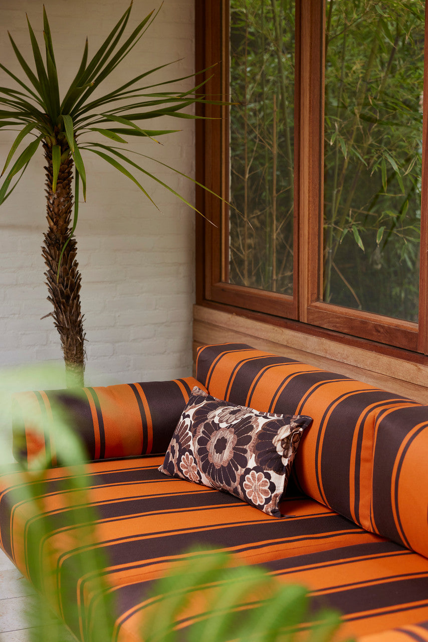 vintage inspired lumbar pillow with brown flowers on a brown orange striped sofa