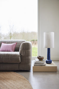 beige linen sofa with pink lumbar shaped pillow and blue table lamp