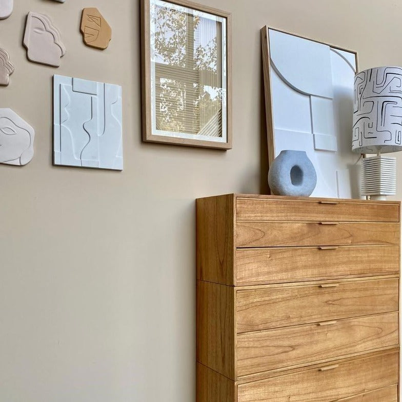 art panel on wall with faces from Peru and a framed paper art work