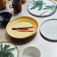 table setting with yellow plate, white breakfast plate and plate with green palm tree