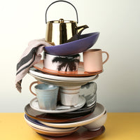 stack of colorful ceramics including a natural linen striped napkin