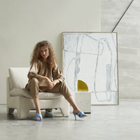 woman on lounge chair with brutalism painting against wall