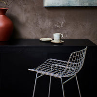 chrome colored counter bar stool against a black bar 