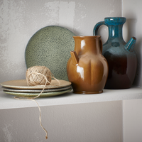 gradient ceramics plates in earth tones next to a brown and blue ceramic jar
