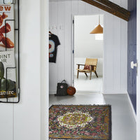peek through hallway to room with wicker chair with red tiger print lumbar pillowl
