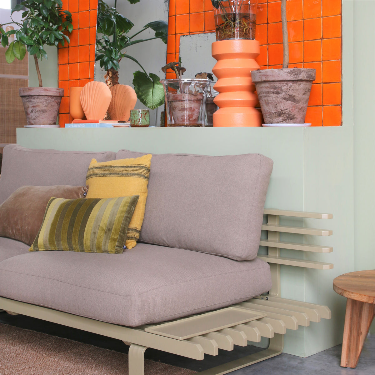 outdoor / indoor sofa in an olive color with glass planter with stoneware inside planter